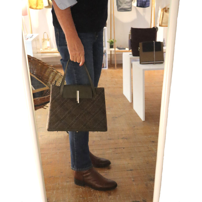 Un petit sac trapèze féminin en Tweed irlandais et cuir bronze porté